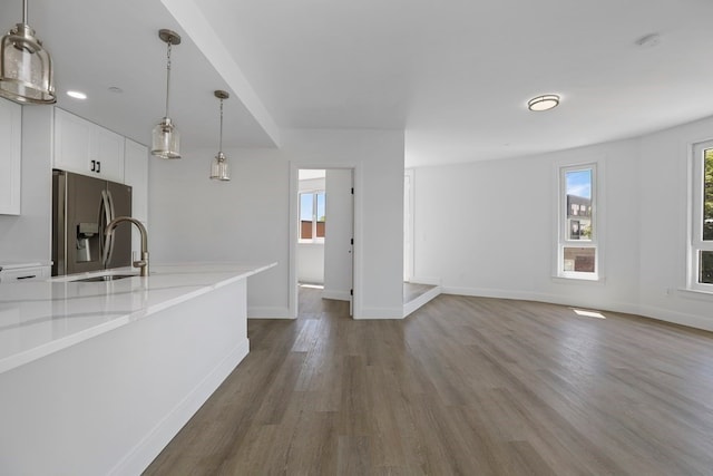 kitchen with pendant lighting, light stone counters, dark wood-type flooring, white cabinetry, and stainless steel refrigerator with ice dispenser