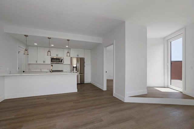 kitchen with white cabinets, hanging light fixtures, sink, stainless steel appliances, and dark hardwood / wood-style floors