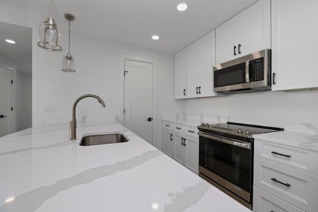 kitchen featuring light stone countertops, white cabinets, appliances with stainless steel finishes, and sink