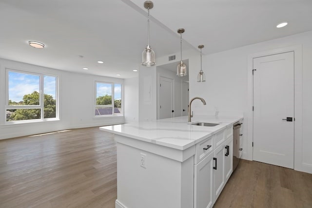 kitchen featuring light wood-type flooring, sink, white cabinets, decorative light fixtures, and light stone countertops