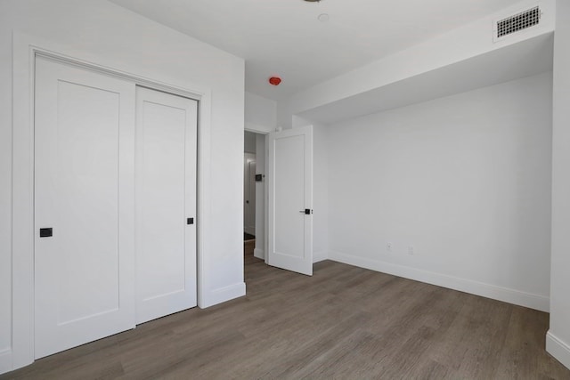 unfurnished bedroom with a closet and dark hardwood / wood-style flooring