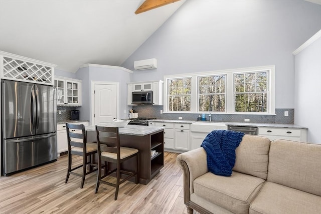 kitchen featuring white cabinets, appliances with stainless steel finishes, a center island, a wall mounted AC, and beam ceiling