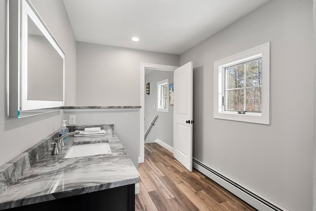 bathroom featuring baseboard heating, hardwood / wood-style floors, and vanity