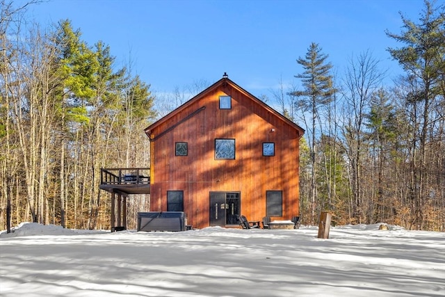 snow covered back of property with a deck