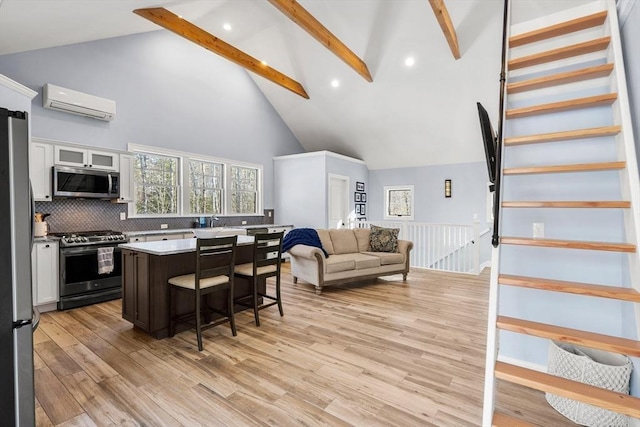 kitchen featuring a center island, a kitchen bar, white cabinetry, stainless steel appliances, and beamed ceiling