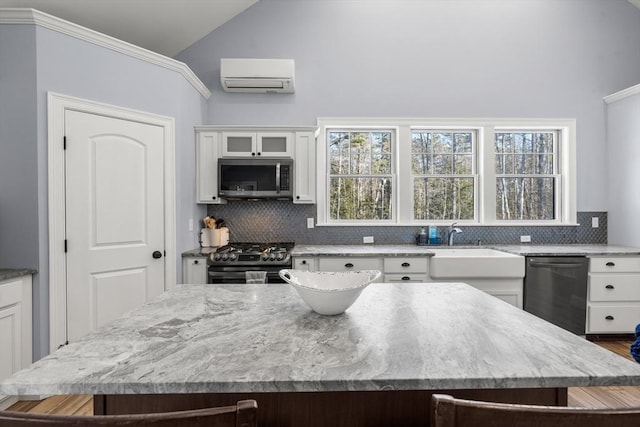 kitchen featuring vaulted ceiling, appliances with stainless steel finishes, white cabinetry, a wall mounted air conditioner, and a kitchen island