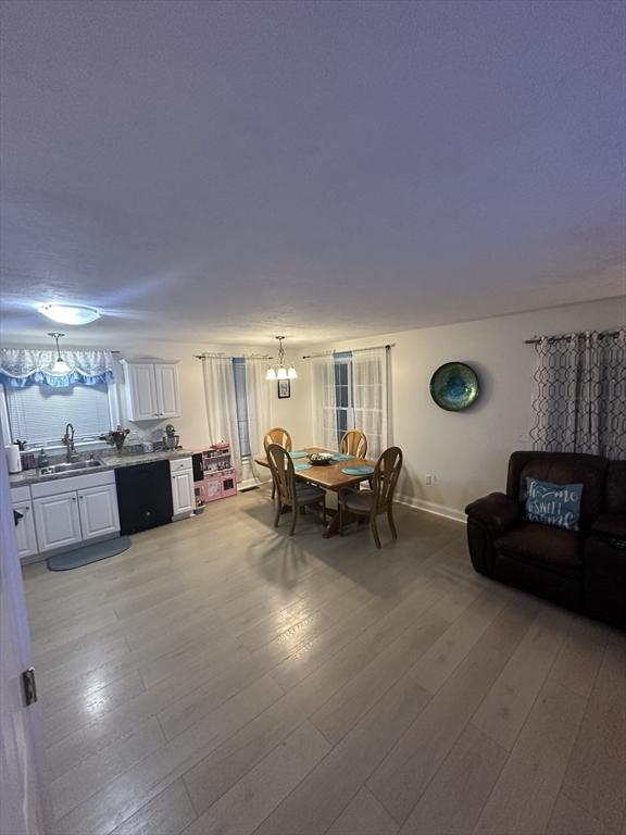 dining area with baseboards, light wood-style floors, and an inviting chandelier