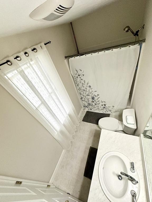 full bathroom featuring a shower with shower curtain, toilet, and a sink