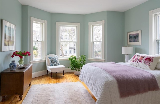 bedroom featuring baseboards, multiple windows, and hardwood / wood-style floors