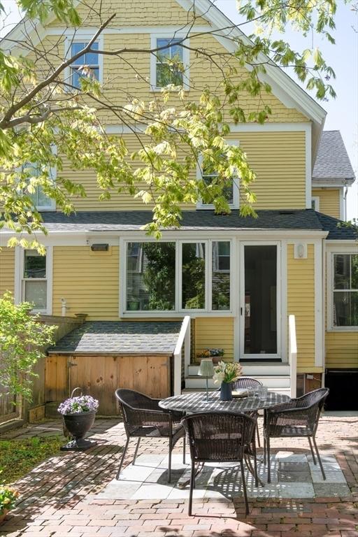 back of property with roof with shingles, a jacuzzi, and a patio area