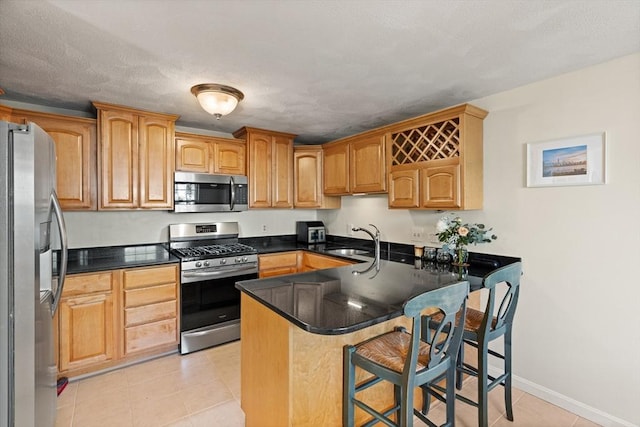 9 Michael Way Unit 41, Andover, MA 01810 - kitchen featuring stainless steel appliances, a sink, a kitchen bar, a peninsula, and light tile patterned flooring