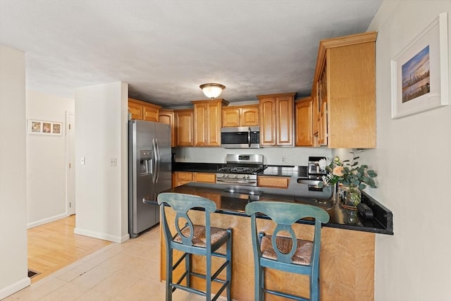 9 Michael Way Unit 41, Andover, MA 01810 - kitchen featuring appliances with stainless steel finishes, a peninsula, dark countertops, a breakfast bar area, and baseboards