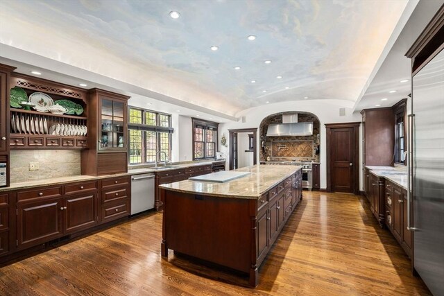 kitchen featuring high quality appliances, dark wood-type flooring, recessed lighting, a kitchen island, and vaulted ceiling