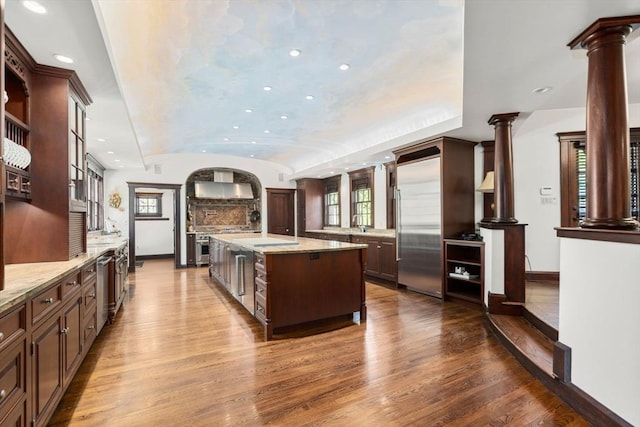 kitchen featuring stainless steel built in refrigerator, dark wood-style floors, baseboards, recessed lighting, and ornate columns