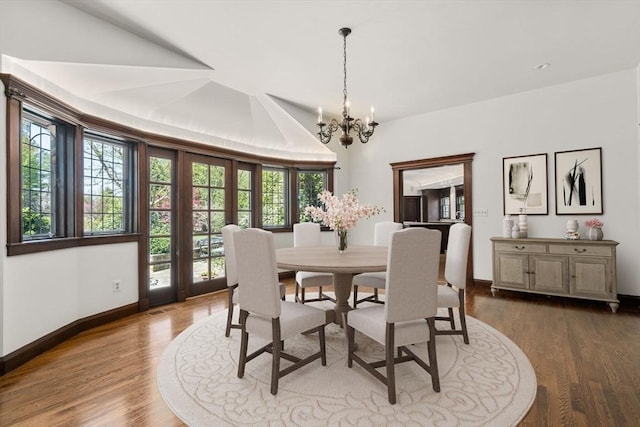 dining area featuring healthy amount of natural light, a chandelier, dark wood finished floors, baseboards, and vaulted ceiling