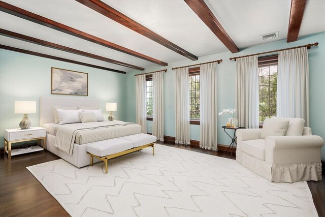 bedroom with beam ceiling, multiple windows, wood finished floors, and baseboards