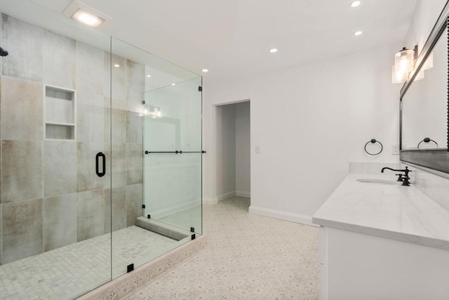 bathroom featuring speckle patterned floor, recessed lighting, baseboards, a stall shower, and vanity