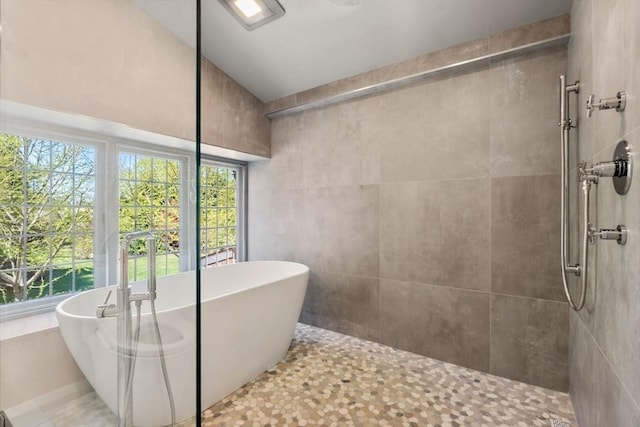 full bath featuring a tile shower, a soaking tub, plenty of natural light, and lofted ceiling
