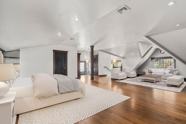 bedroom featuring vaulted ceiling, decorative columns, and wood finished floors