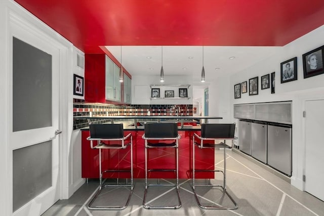 kitchen featuring backsplash, dark countertops, a peninsula, recessed lighting, and a breakfast bar