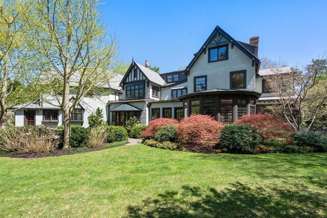 view of front of property featuring a front lawn, stucco siding, and a chimney