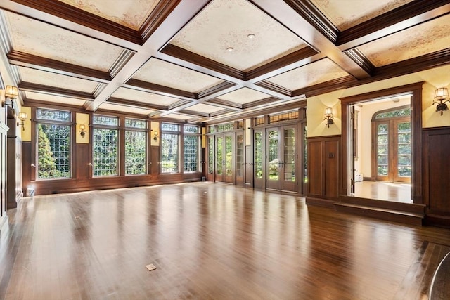 spare room with wood finished floors, coffered ceiling, beam ceiling, crown molding, and a decorative wall