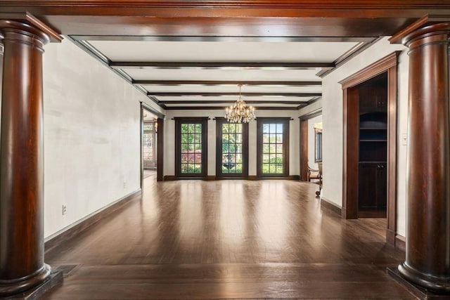 empty room with ornate columns, wood finished floors, a chandelier, baseboards, and beam ceiling