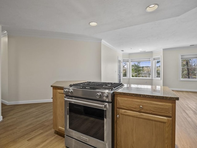 kitchen with crown molding, baseboards, stainless steel gas range oven, and light wood-style flooring