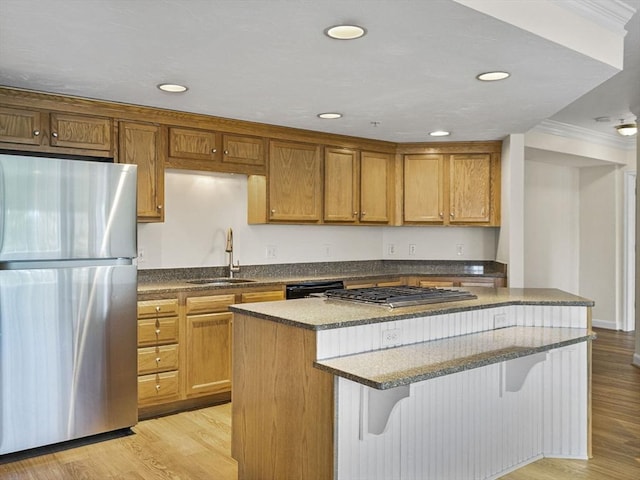 kitchen featuring a breakfast bar area, a center island, a sink, ornamental molding, and stainless steel appliances