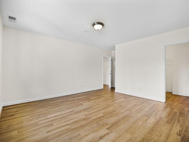 unfurnished room with visible vents, light wood-style flooring, and baseboards