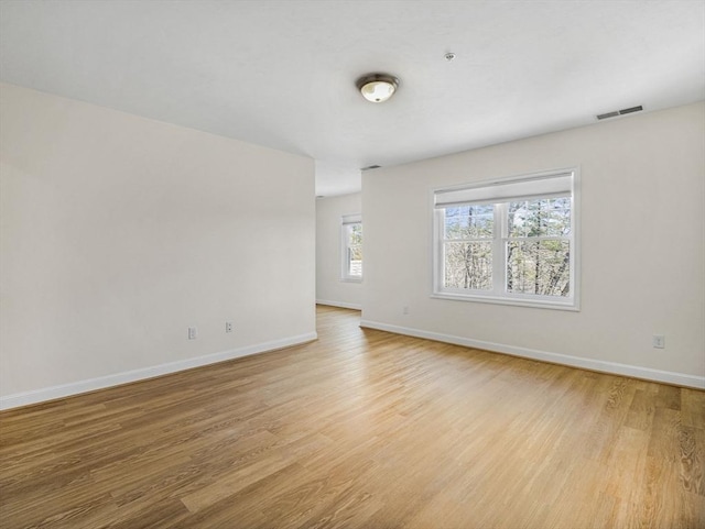 spare room featuring baseboards, light wood-style flooring, and visible vents