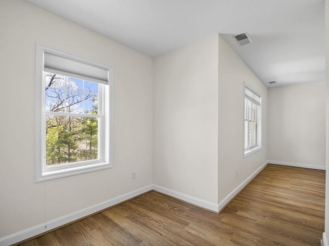 unfurnished room with plenty of natural light, baseboards, and wood finished floors