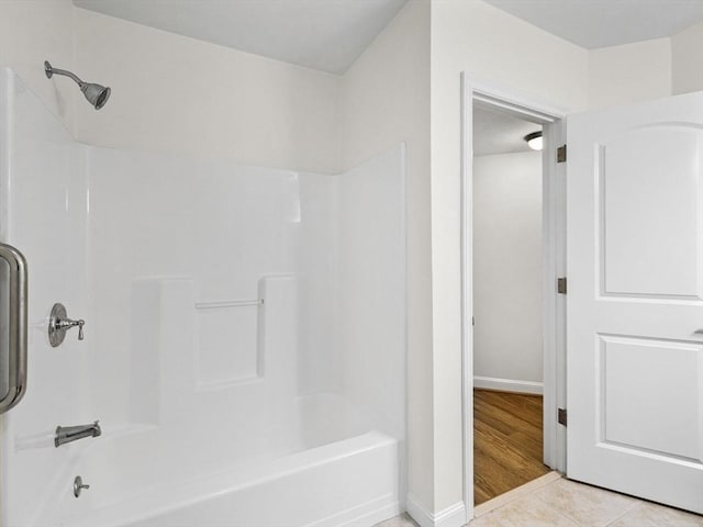 bathroom with baseboards, shower / bathing tub combination, and tile patterned flooring