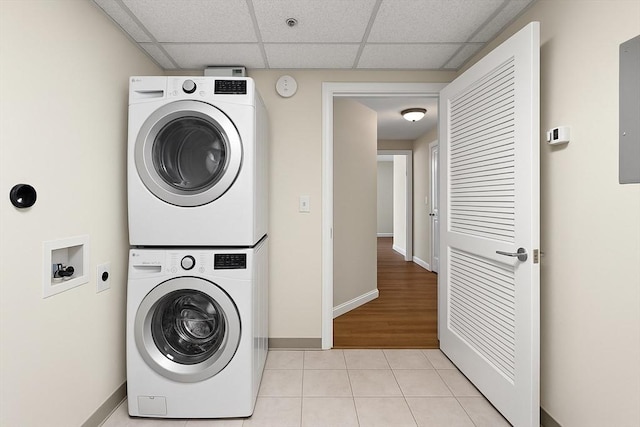 laundry room with light tile patterned floors, baseboards, laundry area, and stacked washer and dryer