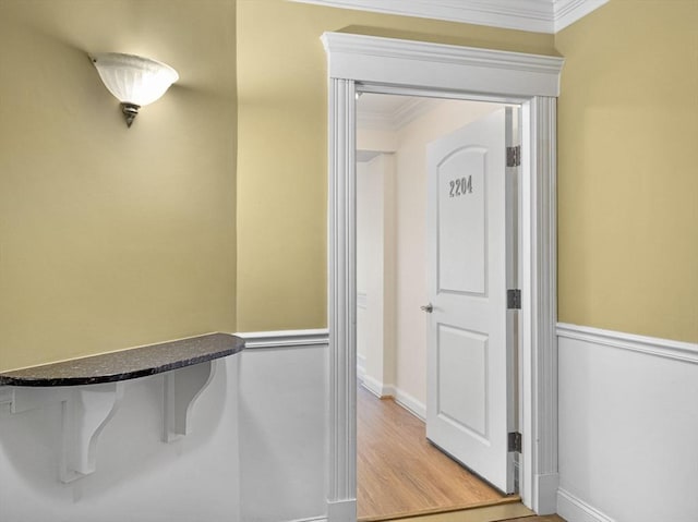 hall with crown molding, baseboards, and light wood-style flooring