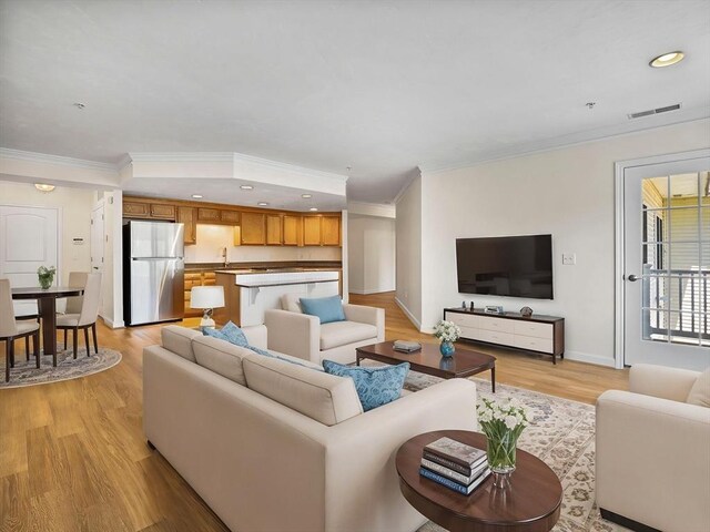 living area featuring crown molding, recessed lighting, light wood-style flooring, and baseboards