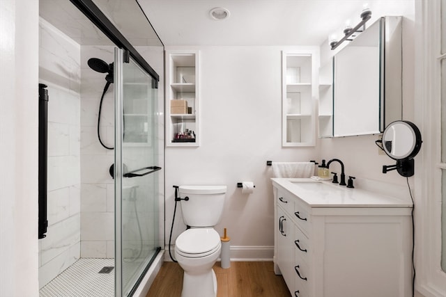 bathroom featuring wood-type flooring, vanity, toilet, and a shower with door