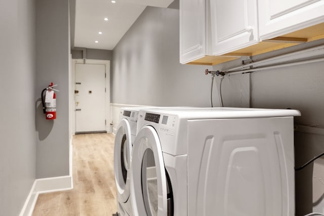 washroom with cabinets, light hardwood / wood-style floors, and washer and dryer