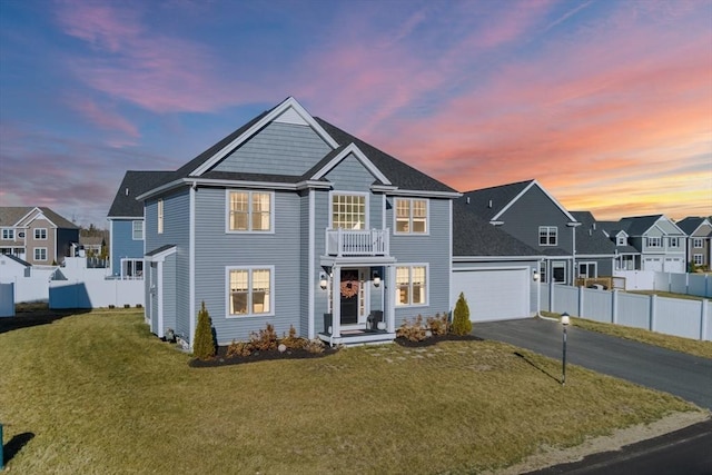 view of front of home featuring a lawn, a balcony, and a garage