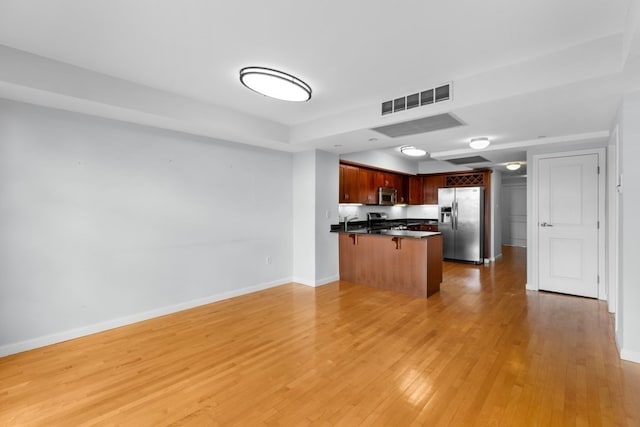 kitchen with stainless steel appliances, a kitchen breakfast bar, wood-type flooring, and kitchen peninsula