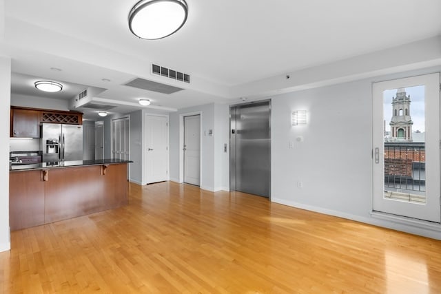 unfurnished living room with elevator and light hardwood / wood-style floors