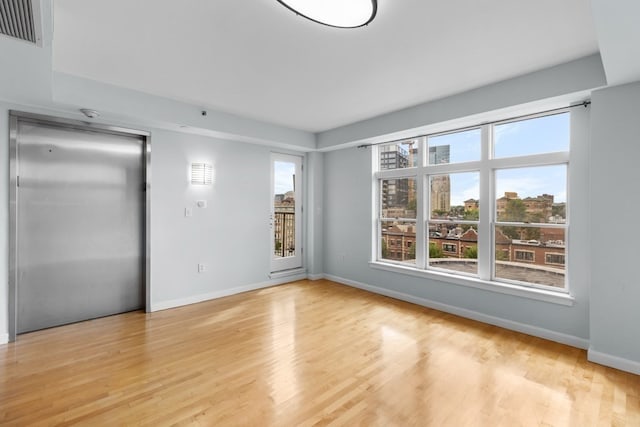 empty room featuring elevator and light hardwood / wood-style floors