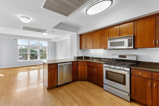 kitchen featuring stainless steel appliances, light hardwood / wood-style floors, kitchen peninsula, and sink