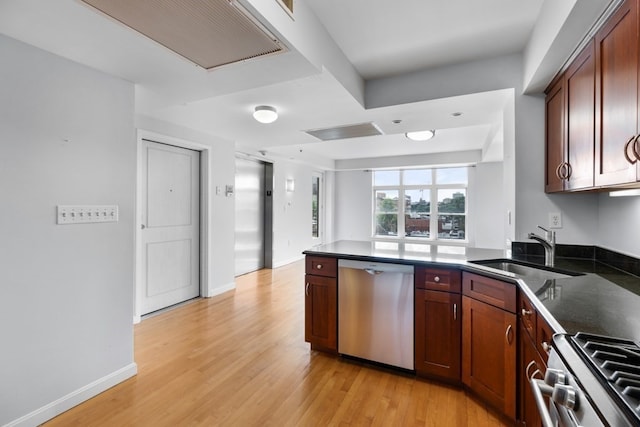 kitchen with kitchen peninsula, sink, appliances with stainless steel finishes, and light hardwood / wood-style floors