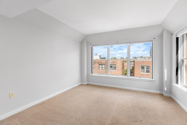 spare room with lofted ceiling and light colored carpet