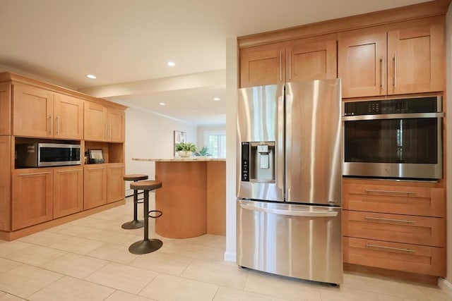 5 Taintor Dr, Sudbury, MA 01776 - kitchen featuring appliances with stainless steel finishes, a kitchen breakfast bar, light brown cabinetry, light stone counters, and recessed lighting