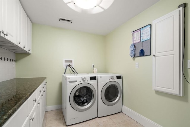 laundry room featuring cabinets, light tile patterned floors, and washer and clothes dryer