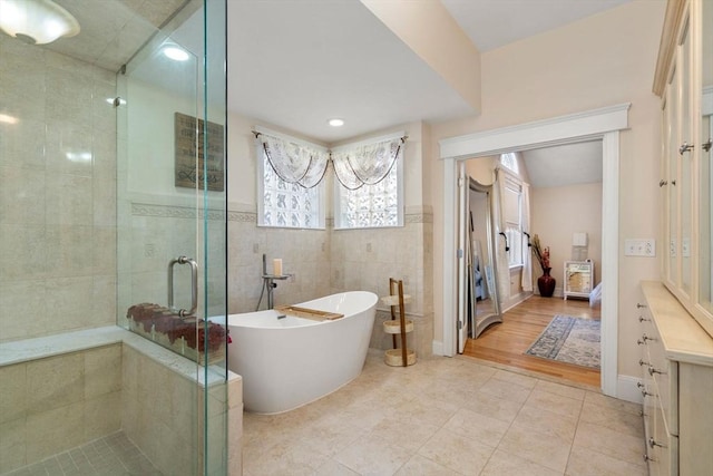 bathroom with vanity, tile patterned flooring, tile walls, and separate shower and tub