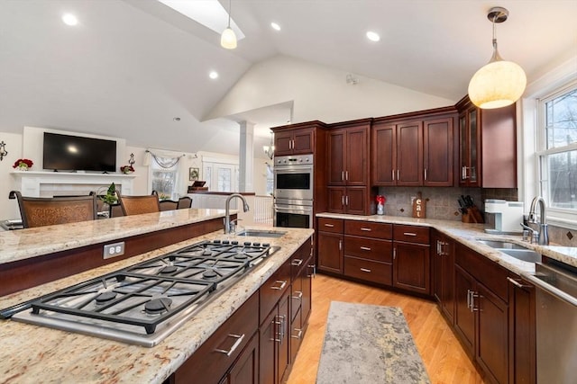 kitchen with stainless steel appliances, sink, hanging light fixtures, and light wood-type flooring