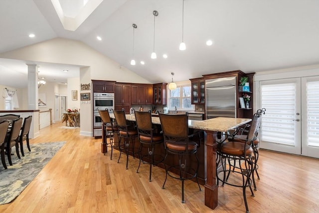 kitchen with pendant lighting, appliances with stainless steel finishes, a kitchen island, and light hardwood / wood-style flooring